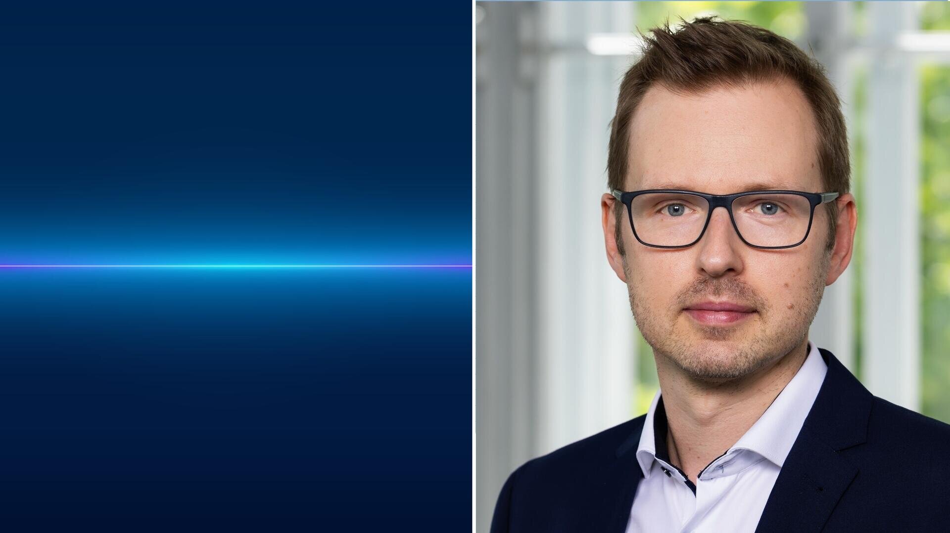 Ein professioneller Mann mit Brille und Anzug posiert vor einem Fenster. Das Bild ist geteilt; die linke Seite zeigt einen minimalistischen blauen Farbverlauf mit einer leuchtenden horizontalen Linie, während die rechte Seite das Porträt zeigt.