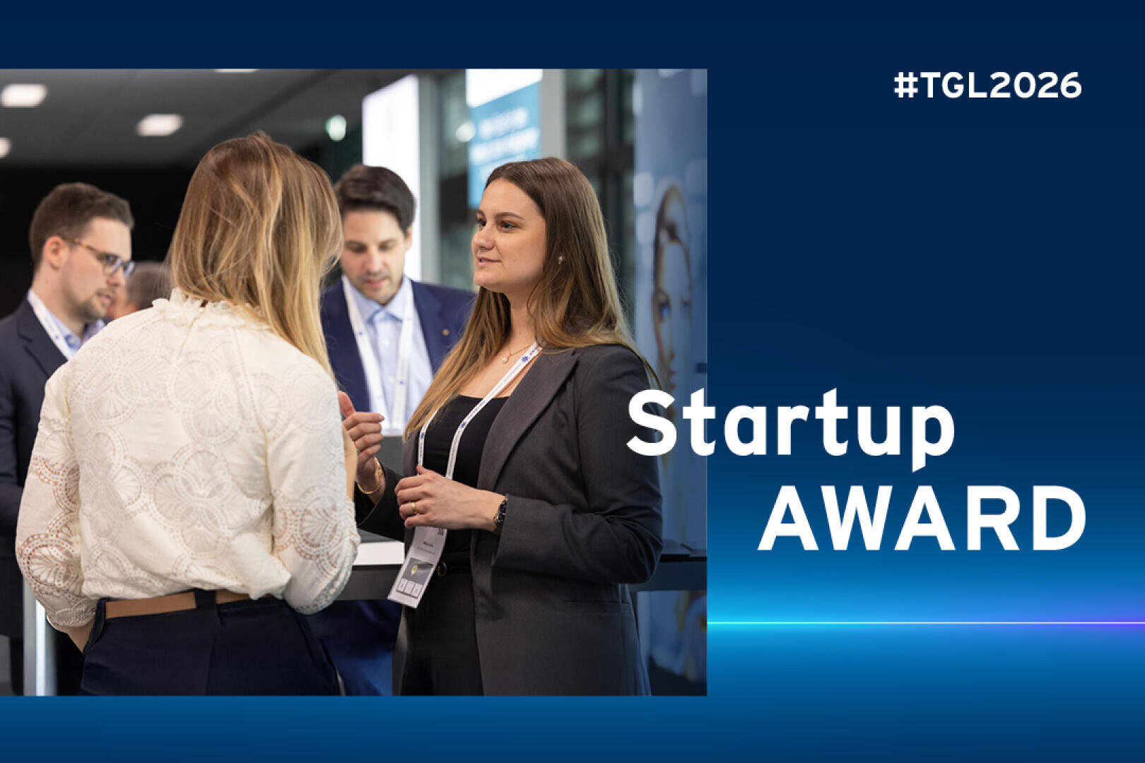 Zwei Frauen in Business-Kleidung unterhalten sich auf einer Fachveranstaltung mit anderen Teilnehmern im Hintergrund. Der Text Startup AWARD und #TGL2026 erscheinen auf der rechten Seite des Bildes.
