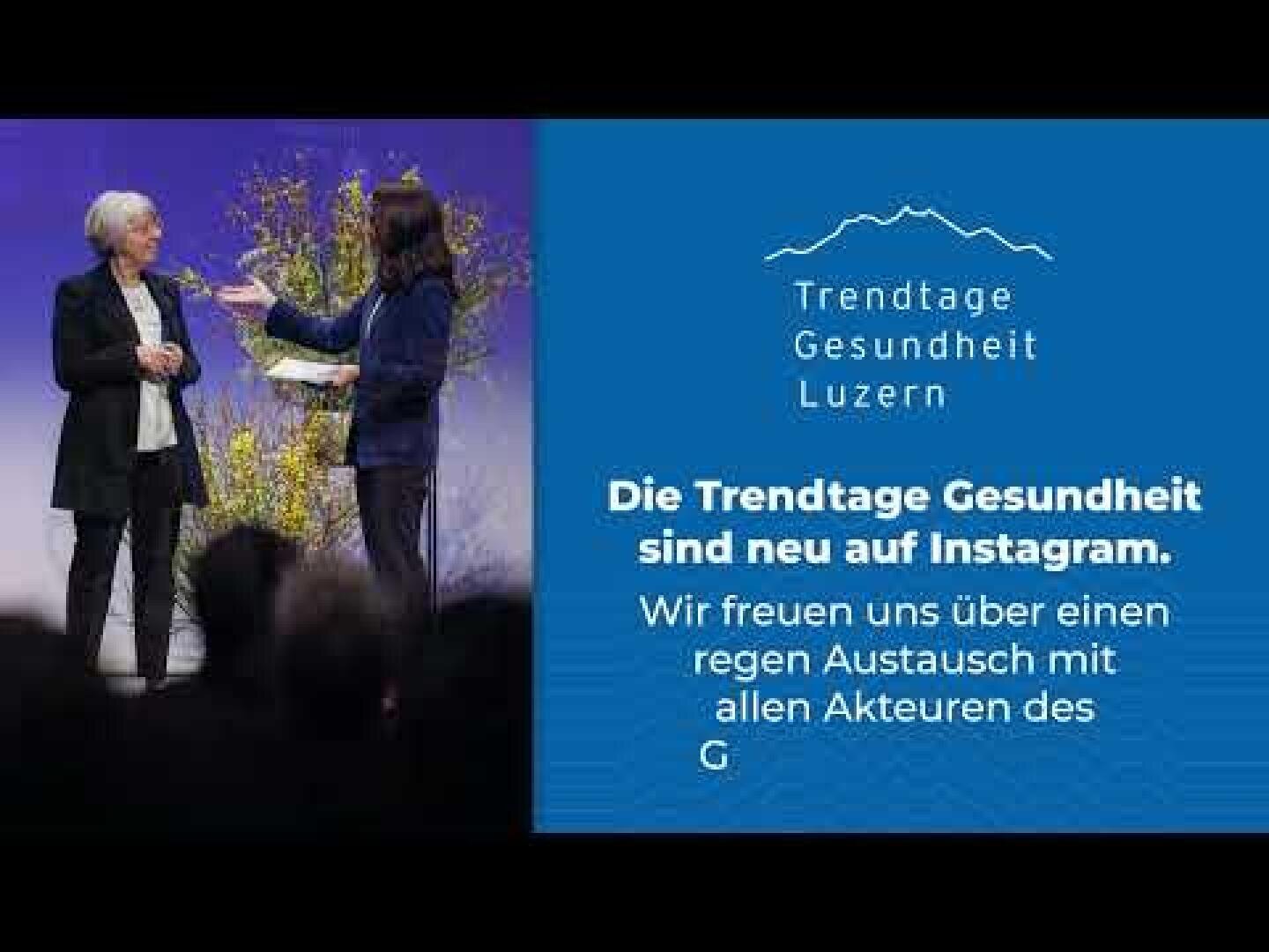 Zwei Frauen sprechen auf der Bühne einer Konferenz. Neben ihnen steht eine blaue Tafel mit dem Logo der Trendtage Gesundheit Luzern und einem Text, der ihre Präsenz auf Instagram ankündigt und zur Interaktion mit den Teilnehmenden auffordert.